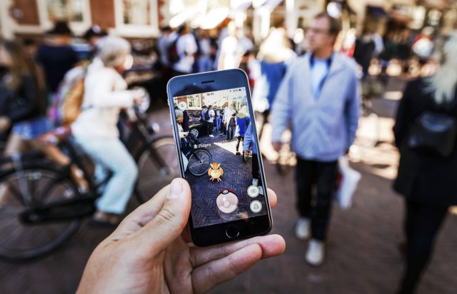 Gamers play with the Pokemon Go application on their mobile phone, at the Grote Markt in Haarlem, on July 13, 2016. / AFP / ANP / Remko de Waal / Netherlands OUT (Photo credit should read REMKO DE WAAL/AFP/Getty Images)